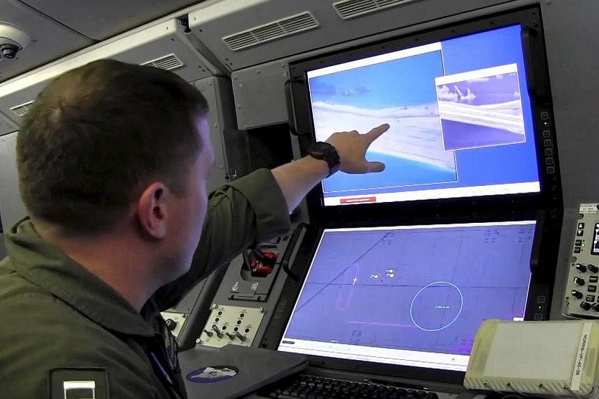 A U.S. Navy crewman aboard a P-8A Poseidon surveillance aircraft views a computer screen purportedly showing Chinese construction on the reclaimed land of Fiery Cross Reef in the disputed Spratly Islands in the South China Sea, in this file still ima