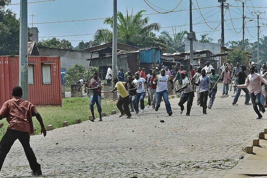 A protestor opposed to the Burundian President's third term confronts members of the Imbonerakure, the youth wing of the ruling party, armed with sticks in the Kimana neighborhood of Bujumbura on May 25, 2015. -- PHOTO: AFP