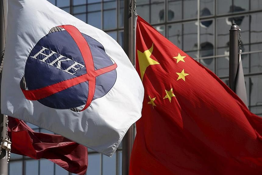A Chinese national flag (right) flies beside a flag of the Hong Kong Exchanges (HKEx) in Hong Kong on April 15, 2015. Hong Kong's exchange operator headed for a record close and brokerages surged on optimism that policy changes in China will spur inf