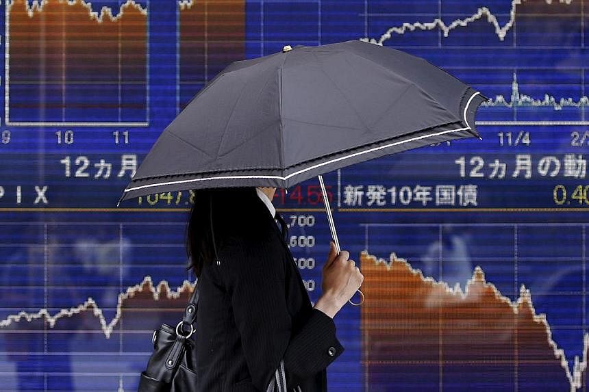 A pedestrian walking past an electronic board showing the graph of the recent fluctuations of Japan's Nikkei average outside a brokerage in Tokyo, Japan, on May 20, 2015. -- PHOTO: REUTERS&nbsp;