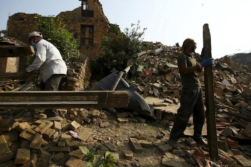 Two men working to clear debris from a collapsed house, a month after the April 25 earthquake in Kathmandu, Nepal on May 25, 2015. -- PHOTO: REUTERS
