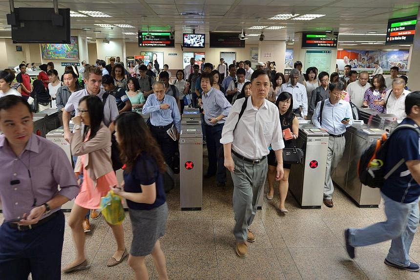 Commuters at Raffles Place MRT station. The Land Transport Authority is extending free pre-peak travel on the rail network for another year, to June 30, 2016. -- PHOTO: ST FILE