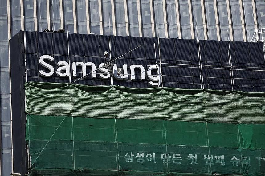 A worker works on a Samsung outdoor advertisement installed atop an office building in central Seoul on March 23, 2015. Samsung Group announced Tuesday the merger of two major affiliates as the South Korean business giant accelerates restructuring ef