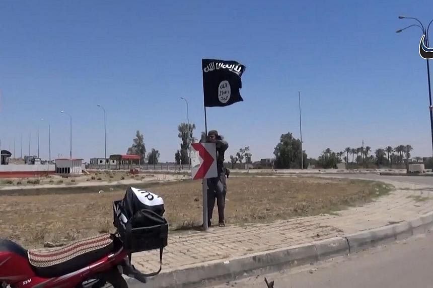 An image grab taken from a video uploaded on May 18, 2015, allegedly showing an ISIS fighter hanging the group's flag in a street of Ramadi, the Iraqi capital of Anbar province, a day after the city was captured by ISIS. -- PHOTO: AFP/HO/AAMAQ NEWS A