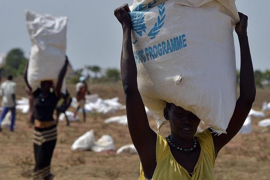 &nbsp;A woman carries a sack of food aid after a food-drop in a field on February 23, 2015 at a village in Nyal, Panyijar county, near the northern border with Sudan.&nbsp;-- PHOTO: AFP