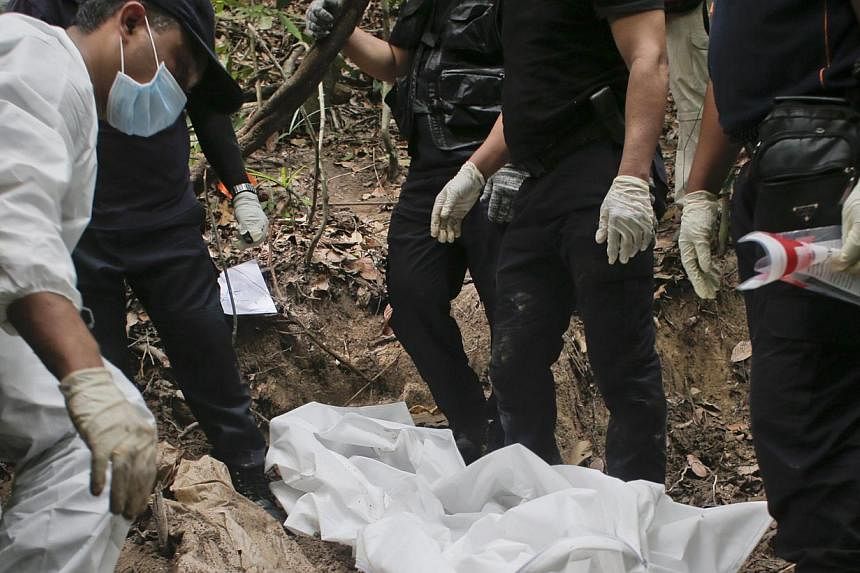 Members of Royal Malaysia Police forensic team exhuming human remains from a grave found at Wang Burma hills at Wang Kelian, Perlis, Malaysia on May 26, 2015. -- PHOTO: EPA