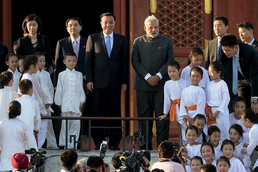 Indian Prime Minister Narendra Modi (centre, right) and Chinese Premier Li Keqiang (centre, left) pose for pictures with child performers of a taiji and yoga event, at the Temple of Heaven park in Beijing, China on May 15, 2015. -- PHOTO: AFP