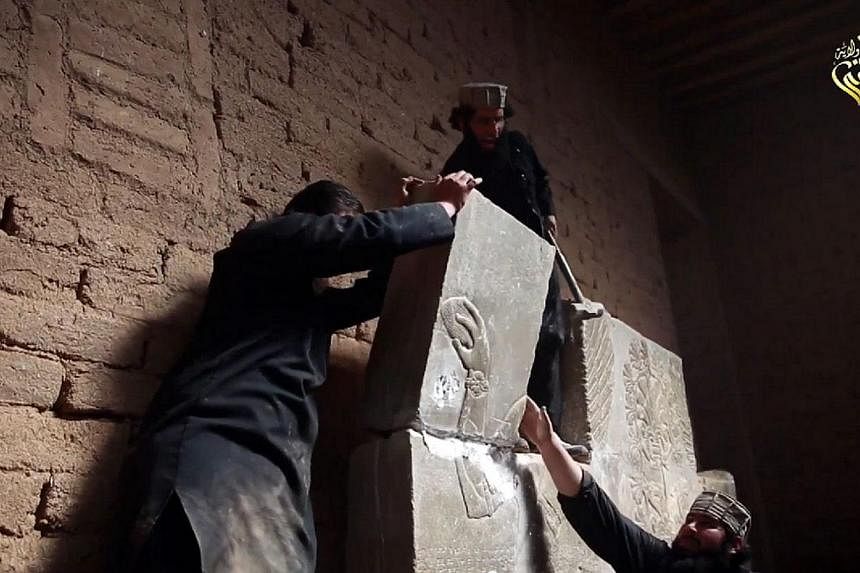 An image grab taken from a video made available by Jihadist media outlet Welayat Nineveh on April 11, 2015, allegedly shows members of the Islamic State (IS) militant group destroying a stoneslab with a sledgehammer at what they said was the ancient 