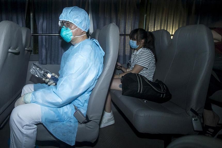 A health worker with protective suits sitting with people (right) who came into close contact with the Korean Mers patient arrive at Lady MacLehose Holiday Village in Sai Kung, where they will spend two weeks in quarantine, in Hong Kong, China on May