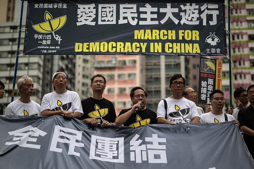 Pro-democracy protesters take turns to speak as they stand behind a huge banner in Hong Kong on May 31, 2015, before a rally to commemorate the 1989 crackdown at Tiananmen Square in Beijing, prior to the incident's 26th anniversary on June 4. Hong Ko