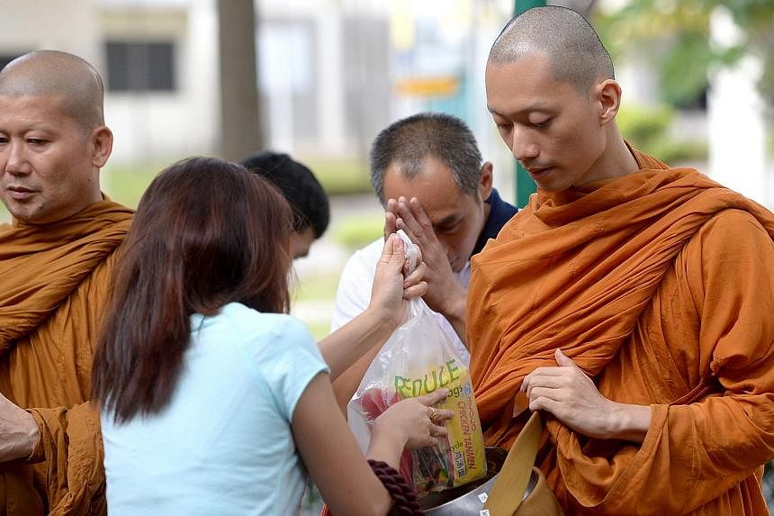 Venerable Goh Chun Kiang collecting cooked food from people at a food centre. The food is then distributed as lunch to the monks and lay people at Palelai Buddhist Temple. -- ST PHOTO: JAMIE KOH