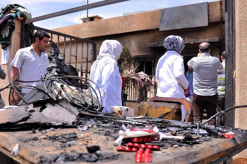 People inspect the damage in the Maysalun clinic where a fire broke out after a fuel tank exploded on May 31, 2015 in the north-eastern city of Qamishli. The fire on Sunday killed 27 people, mostly children, and injured about 30 others, official medi