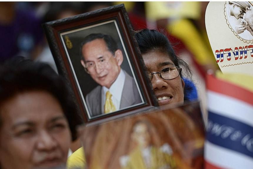 Well-wishers hold portraits of Thai King Bhumibol Adulyadej and wave national flags as they line up the streets outside the Siriraj hospital in Bangkok on May 10, 2015.&nbsp;Thailand's revered but ailing king has returned to hospital in Bangkok for m