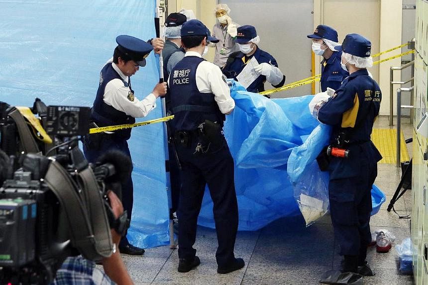 This photograph taken on May 31, 2015 shows police officers inspecting a locker at the Tokyo station. -- PHOTO: AFP