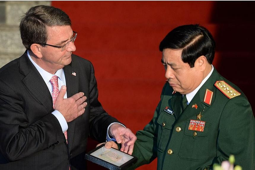 US Defense Secretary Ashton Carter (left) hands over to Vietnamese Defense Minister General Phung Quang Thanh a diary and a belt belonging to Vietnamese communist soldiers combating in the Vietnam War during a joint press conference at the Ministry o