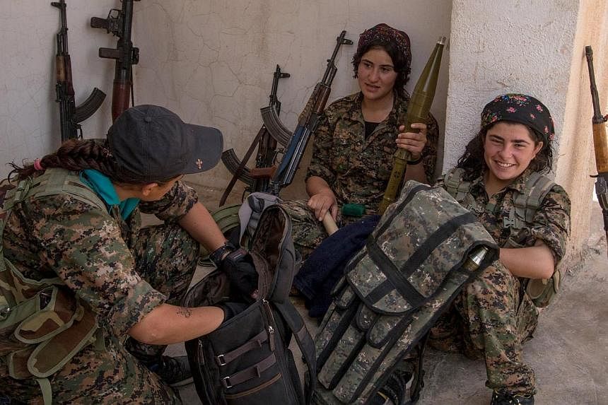 Armed Kurdish female fighters from People's Protection Units (YPG) talk to each other in the Assyrian village of Tel Nasri, western of Tel Tamr town, after the YPG said they retook control of the area from ISIS. -- PHOTO:REUTERS