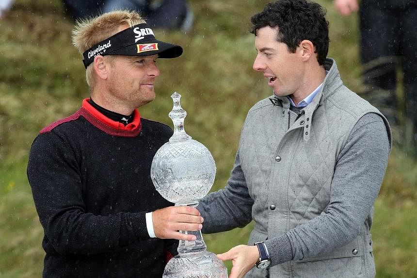 Soren Kjeldsen (left) of Denmark is handed the trophy by Northern Ireland's Rory McIlroy after winning the Irish open at the Royal County Down Golf Club in Newcastle in Northern Ireland on Sunday (May 31). -- PHOTO: AFP