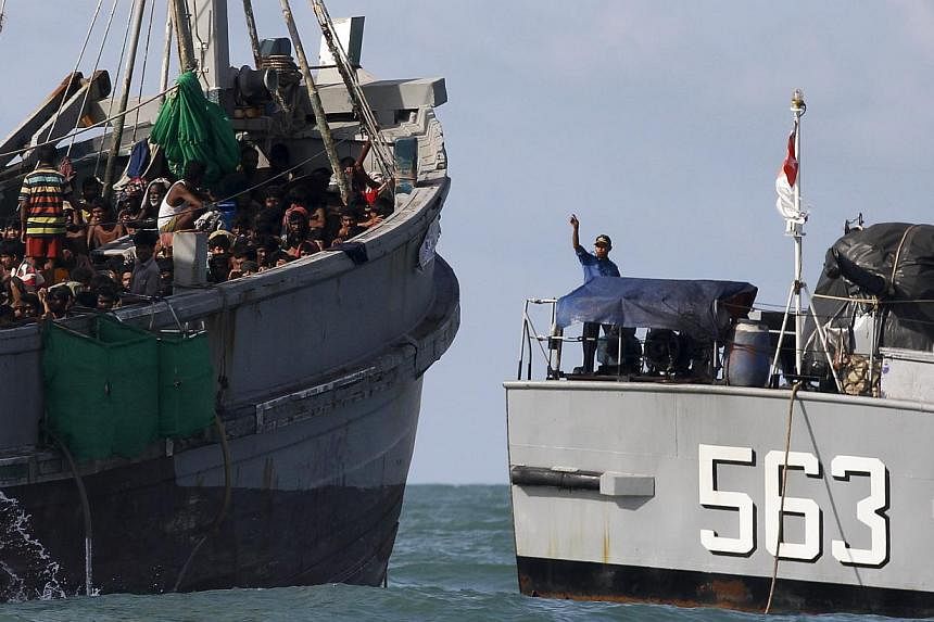 A Myanmar military officer (right) gestures from a navy ship towards a boat packed with migrants, off Leik Island in the Andaman Sea on&nbsp;May 31, 2015. Myanmar's navy is escorting a boat crammed with 727 abandoned migrants to the waters of neighbo
