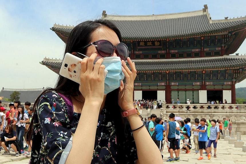 A Chinese tourist wearing a mask to prevent contracting Middle East Respiratory Syndrome (MERS) tours the Gyeongbok Palace in Seoul, South Korea, on June 1, 2015. -- PHOTO: REUTERS&nbsp;