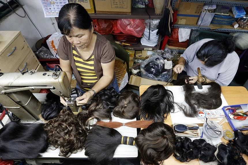 Workers at Singapura Hair Wigs making wigs that will be loaned to cancer patients. It was commissioned by Tan Tock Seng Hospital to make wigs from donated hair - nearly 120 people have pledged their hair.