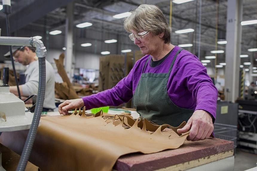 A worker using a die-cutting machine to cut out shapes of leather to be sewn into boots at the L.L. Bean manufacturing facility in Brunswick, Maine, US. -- PHOTO: BLOOMBERG&nbsp;
