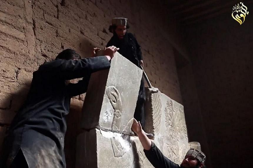 An image grab taken from a video on April 11, 2015, made available by Jihadist media outlet Welayat Nineveh allegedly shows members of the Islamic State in Iraq and Syria (ISIS) destroying a stoneslab with a sledgehammer at what they said was the anc