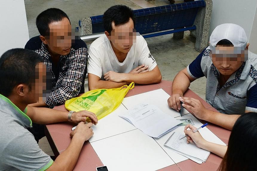 Over 200 workers are living in the dormitory located in the basement carpark of an under-construction condominium, the Chinese daily reported on Tuesday. Some of the affected foreign workers in an interview with a reporter from the daily. - PHOTO: SH