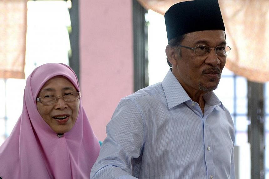 In this file photo taken on May 5, 2013, opposition leader Anwar Ibrahim (right), accompanied by his wife Wan Azizah, casts his vote at a polling station in Permatang Pauh, Penang. -- PHOTO: AFP