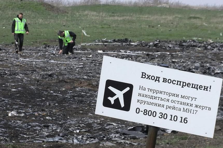 Investigators work near a sign reading "No entrance! There may be remains of the victims of flight MH17 crash at the territory" at the site of the plane's crash near the village of Hrabove (Grabovo) in Donetsk region on April 16, 2015. The Russian fi