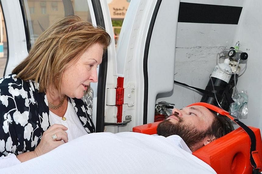 An unidentified woman speaks to an American, believed to have been held by Iran-backed Houthis, as he lays on a stretcher upon his arrival in Oman. An unidentified Singaporean was also released, and may have been among several people held by Iran-bac