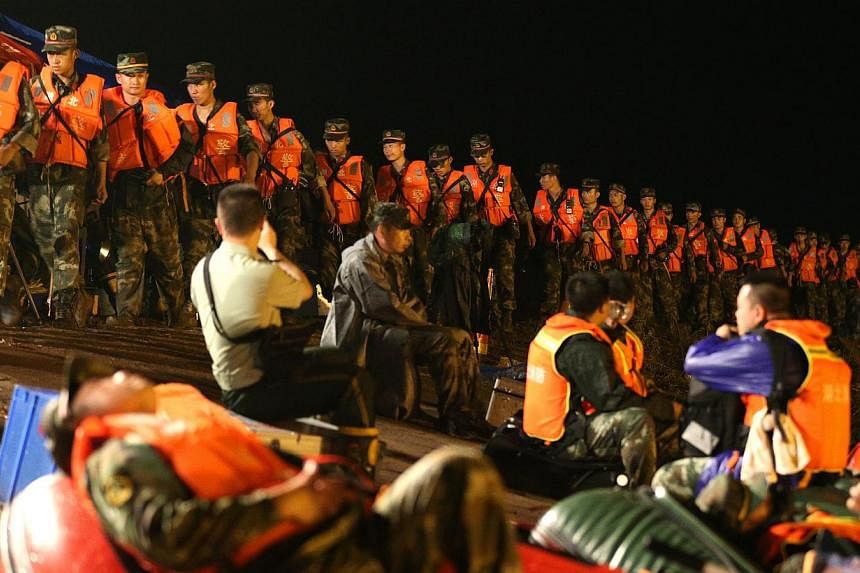 Rescuers walk in a line along the bank side of the Yangtze River as they search for missing passengers of a capsized tourist ship in Jianli, Hubei province, China, on June 2, 2015. -- PHOTO: EPA&nbsp;