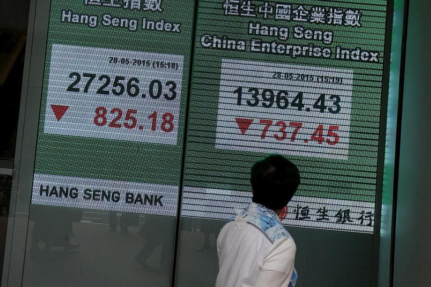 A passerby looking at a panel displaying the blue-chip Hang Seng Index outside a bank during afternoon trading in Hong Kong, China on May 28, 2015. -- PHOTO: REUTERS