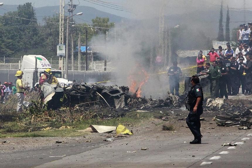 Mexican firefighters and members of Mexican Federal Police inspecting the site where a small plane crashed on the highway between Mexico City and Queretaro, Mexico, on June 2, 2015. -- PHOTO: EPA