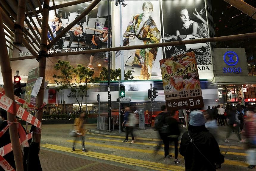 An attendant carries an advertisement of a Japanese restaurant as people cross at street at Causeway Bay shopping district in Hong Kong on March 26, 2015. -- PHOTO: REUTERS