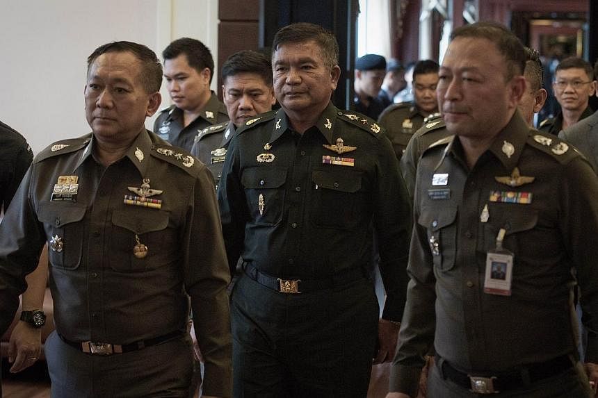 Thai Army Lieutenant General Manas Kongpan (centre) is surrounded by police officers as he turns himself in at the police headquarters in Bangkok on June 3, 2015. -- PHOTO: AFP