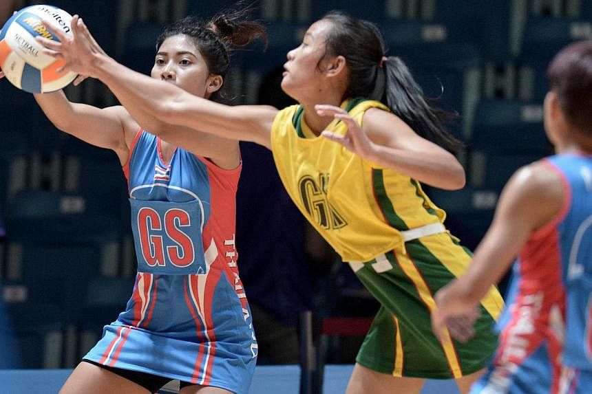 Thailand's Yada Boonkong (left) competes with Myanmar Mon Khin Aye (centre) during the women's netball preliminary round between Thailand and Myanmar at the 28th SEAgames 2015 in Singapore on June 3, 2015. -- PHOTO: AFP