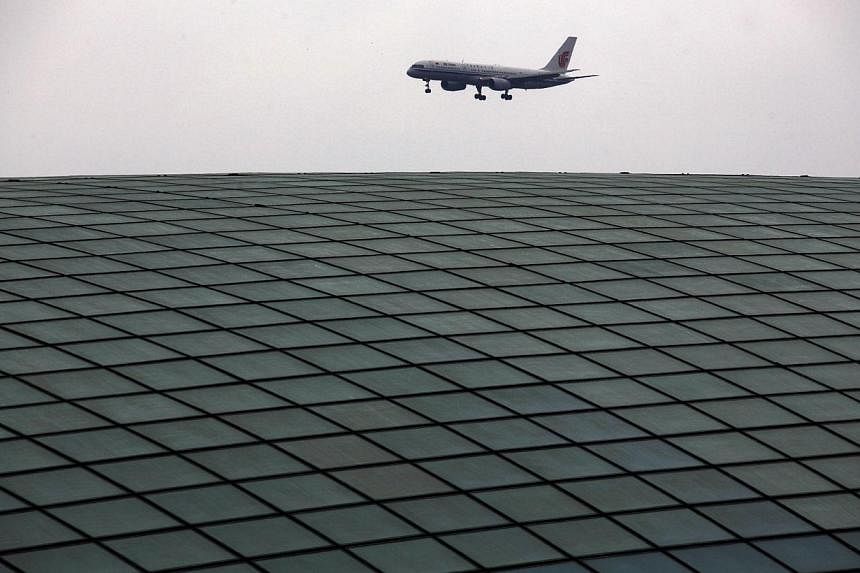 An Air China plane comes in to land over the roof of the railway station at Beijing's internationl airport in this April 21, 2011 file photo. -- PHOTO: REUTERS