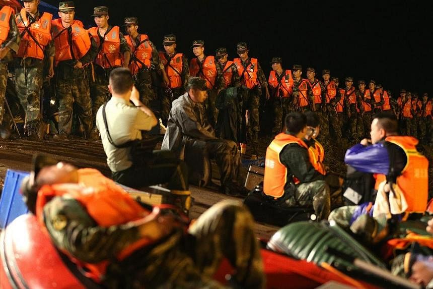 Rescuers walk in a line along the bank side of the Yangtze River as they search for missing passengers of a capsized tourist ship in Jianli, Hubei province, China, late Tuesday (June 2). -- PHOTO: EPA