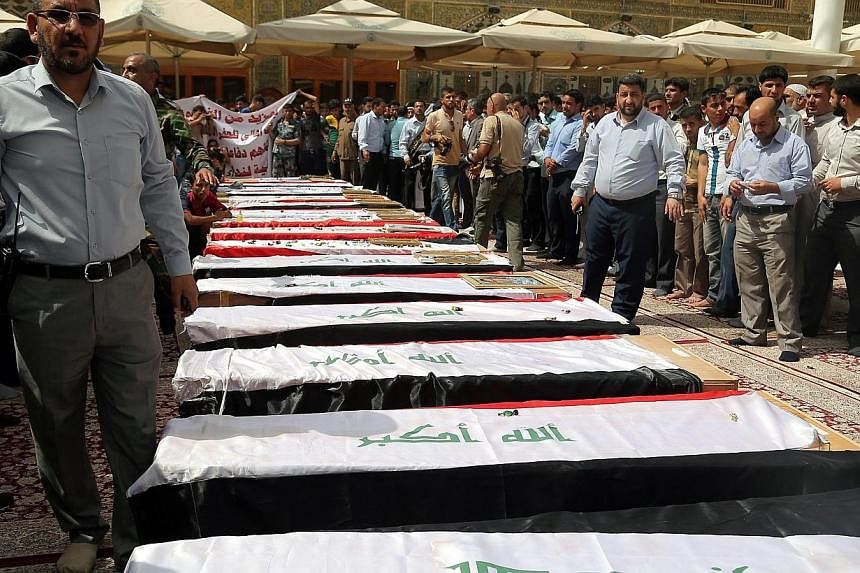 Iraqis stand next to the coffins of Iraqi soldiers believed to have been killed in a suicide attack by ISIS fighters at the base in Tharthar area northern Ramadi, during the funeral processions in Najaf, southern Iraq, on Tuesday (June 2). -- PHOTO: 