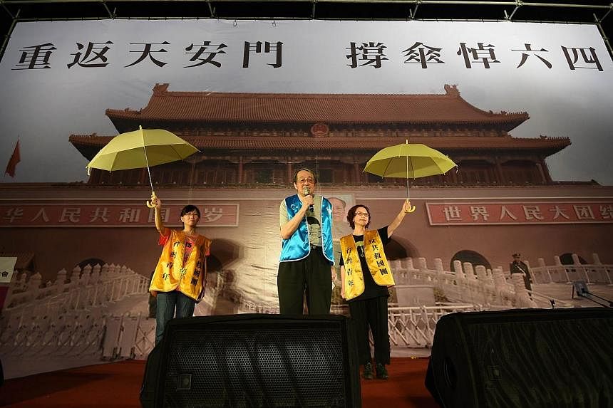 Pro-Taiwan independent activists display a yellow umbrellas in front of a poster showing Beijing's Tiananmen square during a candlelit vigil in Taipei on June 4, 2015. -- PHOTO: AFP