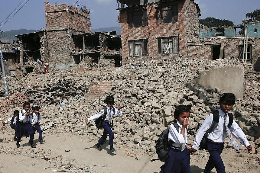 Nepalese children pass damaged houses in Bungmati, Kathmandu, Nepal on May 31,&nbsp;2015, which were damaged by the earthquake on April 25,&nbsp;2015. -- PHOTO: EPA