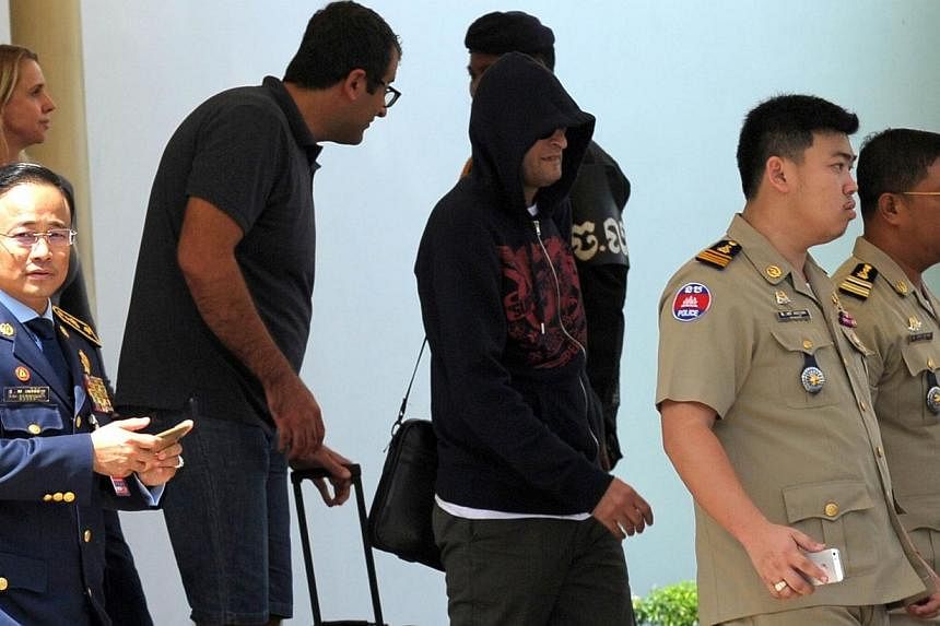 A refugee (third from right) held under Australian custody is escorted by Cambodian police following his arrival at the Phnom Penh International airport on June 4, 2015. -- PHOTO: AFP