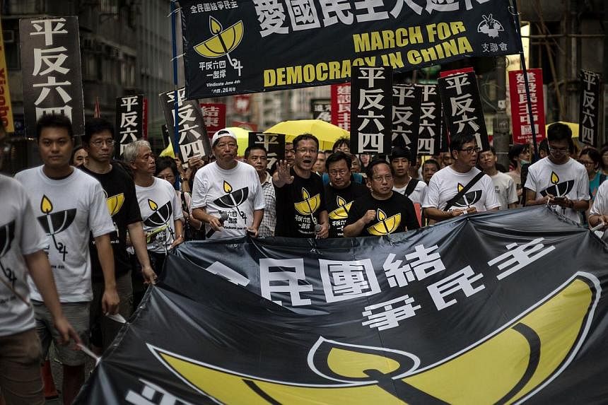 Members of the pro-democracy movement hold a huge banner as they attend a rally in Hong Kong on May 31, 2015, to commemorate the 1989 crackdown at Tiananmen Square in Beijing, prior to the incident's 26th anniversary on June 4. -- PHOTO: AFP