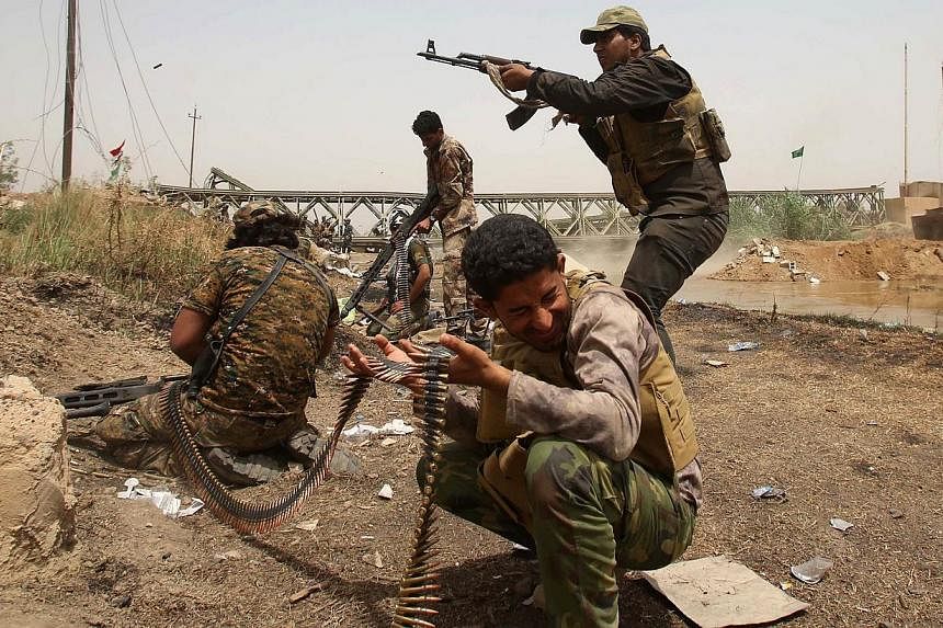 Members of the Popular Mobilisation units opens fire during a fight with ISIS militants in the area of Sayed Ghareeb, near Dujail, some 70km north of Baghdad, on May 28, 2015. -- PHOTO: AFP