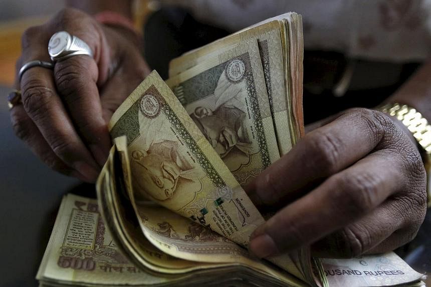A money lender counts Indian rupee currency notes at his shop in Ahmedabad, India. -- PHOTO: REUTERS