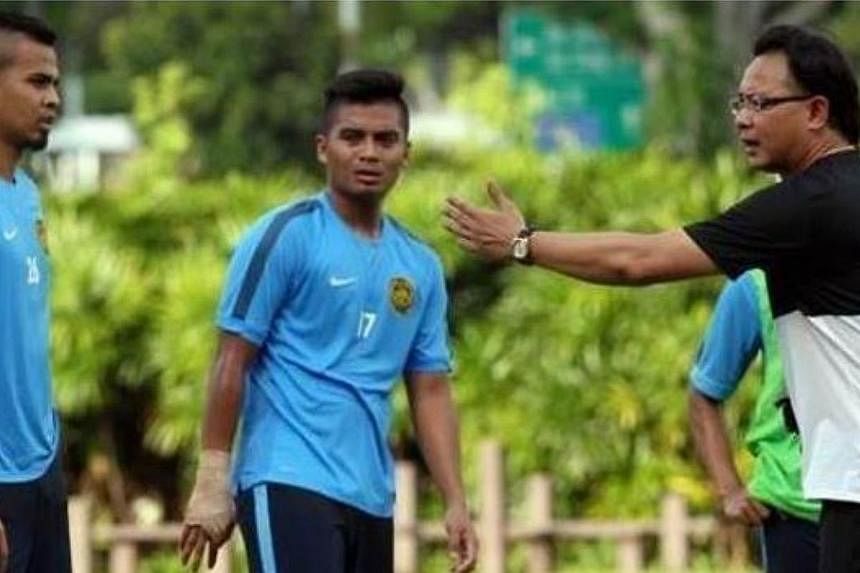 Malaysian national football coach Ong Kim Swee (right) giving instructions to his players during their training at the ITE Sports Complex in Singapore on May 28, 2015. Ong's men are on the verge of elimination from the SEA Games, after a 5-1 drubbing