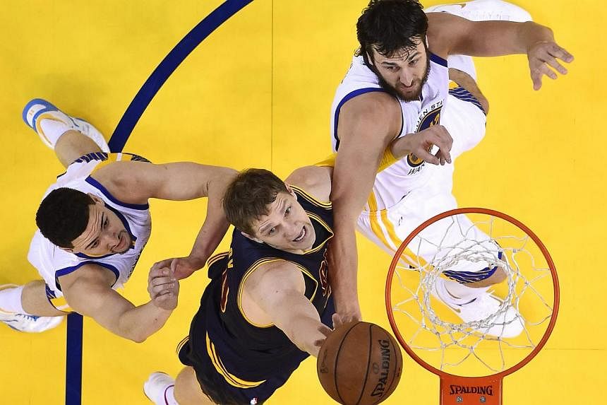 Cleveland Cavaliers player Timofey Mozgov (centre) going for a rebound against Golden State Warriors players Andrew Bogut (right) and Klay Thompson (left) in the first half of Game One of the NBA Finals in Oakland, California, on June 4, 2015. -- PHO
