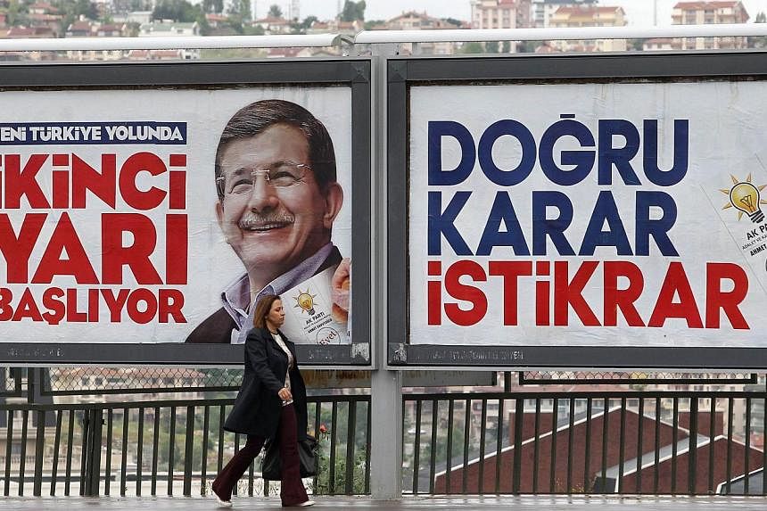 A woman walking in front of a campaign poster of Turkish Prime Minister Ahmet Davutoglu in Ankara Turkey, on June 4, 2015. -- PHOTO: AFP&nbsp;