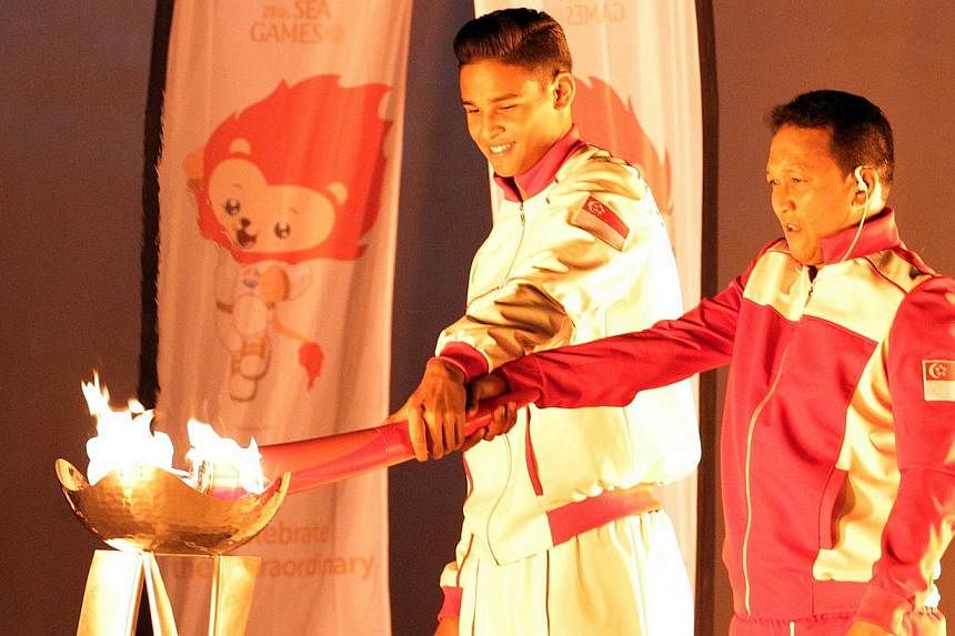 Former national footballer Fandi Ahmad (right) lighting the SEA Games cauldron with his eldest son Irfan Fandi. -- ST PHOTO: SEAH KWANG PENG
