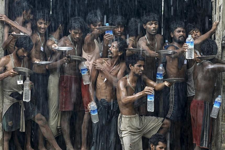 Migrants, who were found at sea on a boat, collecting rainwater during heavy rainfall at a temporary refugee camp near Kanyin Chaung jetty, outside Maungdaw township, northern Rakhine state in Myanmar, on June 4, 2015. -- PHOTO: REUTERS&nbsp;